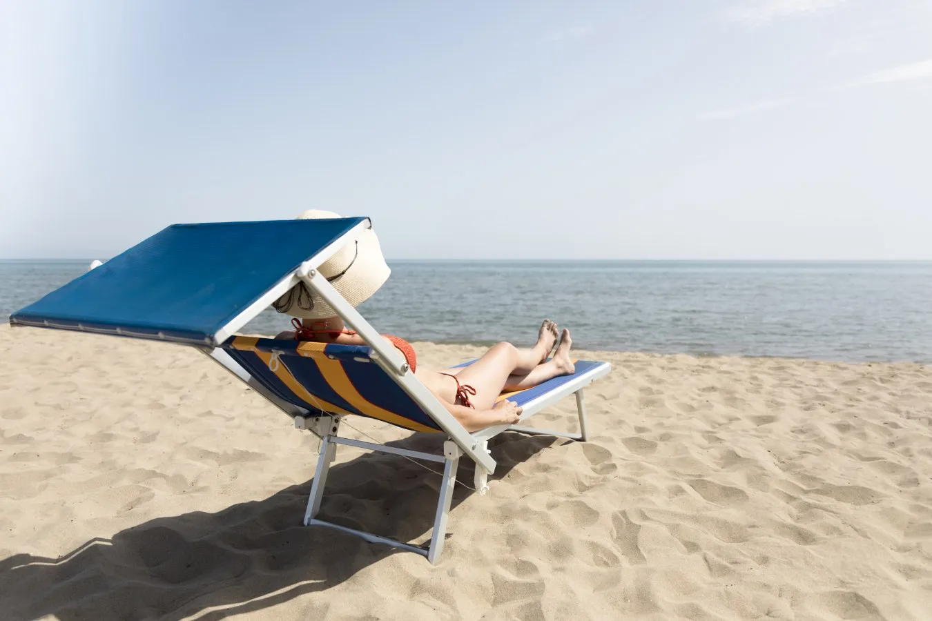 Mujer sentada en playa. La menstruación y las vacaciones